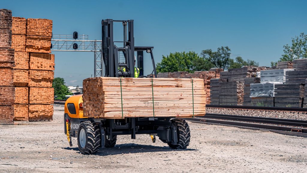 GoLoadMac truck mounted forklift in use at a lumber yard, unloading lumber.