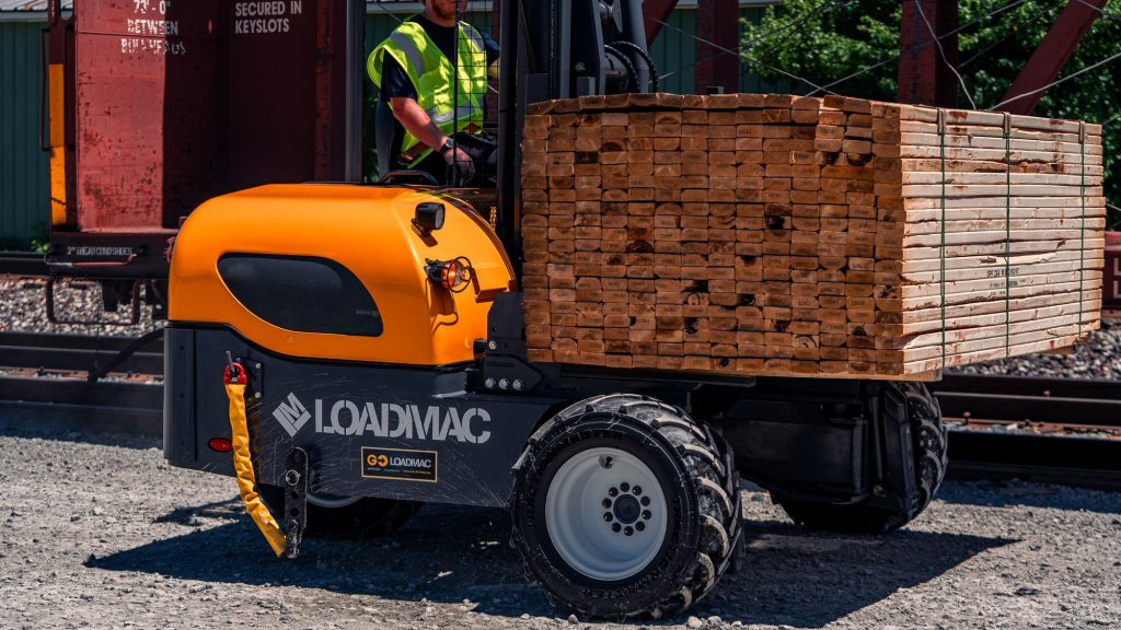 GoLoadMac truck mounted forklift in use at a lumber yard, unloading lumber.