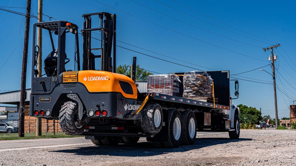 GoLoadMac truck mounted forklift in use at a lumber yard, unloading lumber.